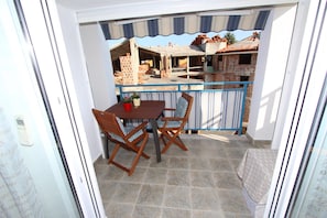 A balcony with a table and chairs, a potted plant, and a view of a building under construction. - Apartment Ala (Rovinj)