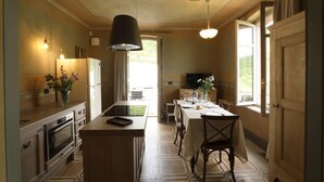 Een keuken met een centraal eiland, een inbouwoven en een eethoek met een tafel en stoelen.