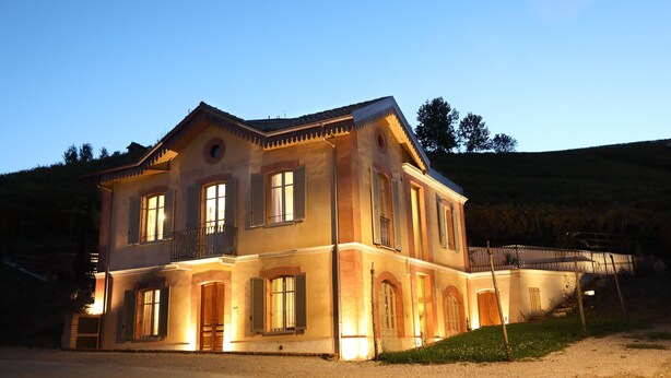 A two-story building with a balcony, large windows, and a well-lit entrance. - Apartment Alba 4 in Villa Giobatta (Barolo)