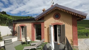 A villa with a patio, outdoor seating, and a view of the surrounding hills. - Appartamento Monforte 4 in Villa (Barolo)