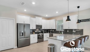 A modern kitchen with white cabinets, stainless steel appliances, and a central island with bar stools.