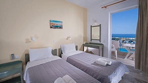Habitación de hotel con dos camas, un balcón y vistas a la piscina, además de un pequeño escritorio.