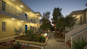 Un patio con un sendero de piedra, plantas en macetas y una puerta azul.