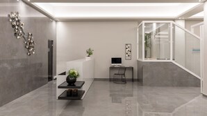 Un hall d’entrée moderne avec un comptoir d’accueil, un ordinateur, une chaise et un escalier.