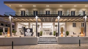 Une entrée d’hôtel moderne avec un espace extérieur couvert, des marches menant à l’entrée et une enseigne indiquant « Meliá Oasis ».