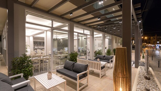 Un espace extérieur aménagé avec des tables et des chaises, une colonne décorative et une vue sur la salle à manger intérieure.
