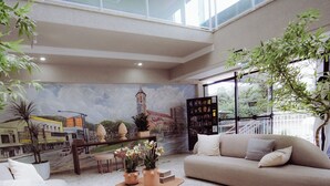A modern living room with a beige sofa, a coffee table, and a mural of a cityscape on the wall.