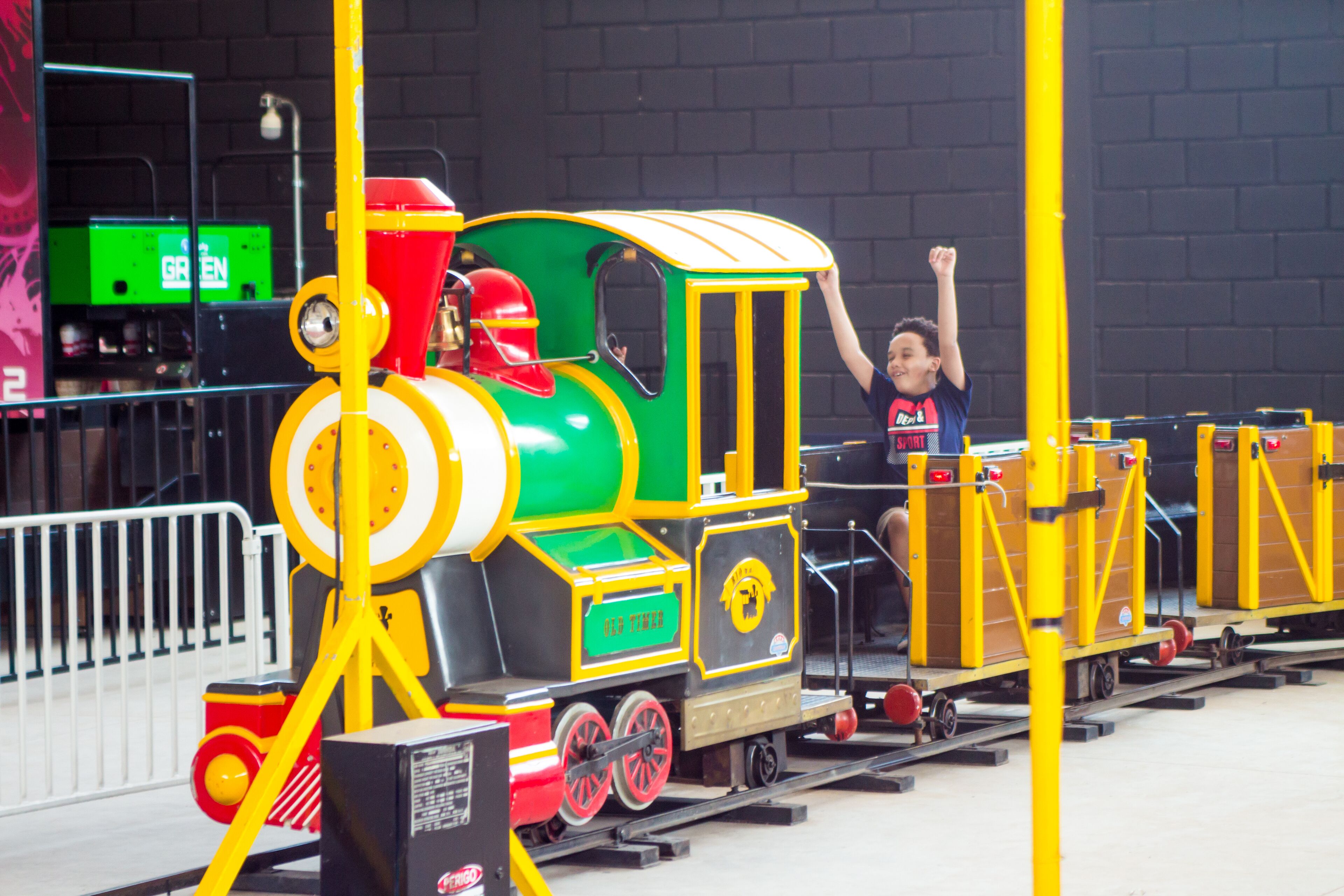 A miniature train ride with a child seated in the front.