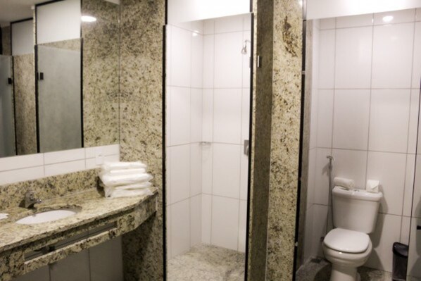 Un baño con encimera de granito, lavamanos, espejo, cabina de ducha y retrete.