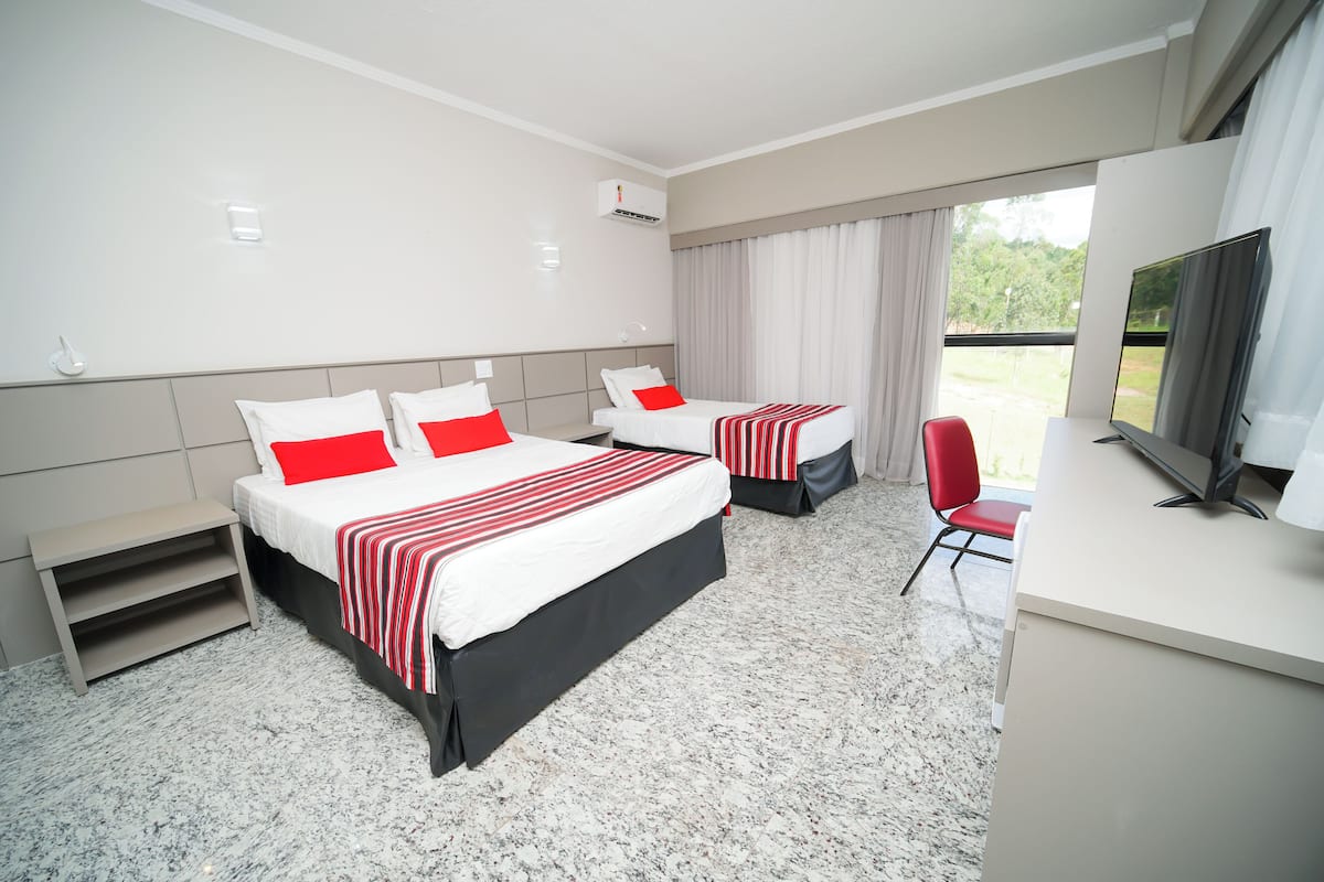 A hotel room with two beds, a desk, a chair, and a TV.