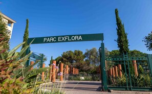 A gated entrance labeled "PARC EXFLORA" with a clear pathway leading through it.