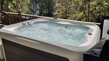 A hot tub on an outdoor deck with a view of trees and a private road sign.