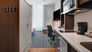 A compact hotel room with a kitchenette, a bed, a desk, and a chair. - TownePlace Suites by Marriott Cincinnati Downtown (Cincinnati)