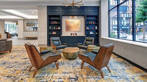 A modern lobby with a round coffee table, leather armchairs, a large abstract painting, and a view of the street through large windows. - TownePlace Suites by Marriott Cincinnati Downtown (Cincinnati)
