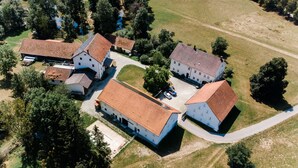 An aerial view of a residential area with multiple buildings, a paved road, and surrounding greenery.