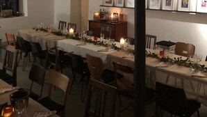 A dining area with multiple tables set for a meal, featuring candles and table settings.
