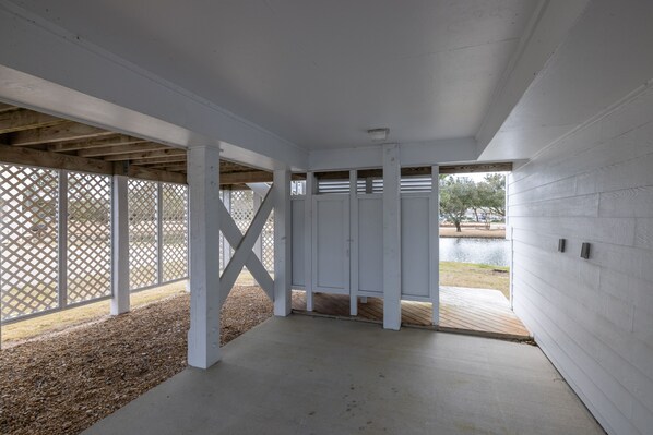 An empty covered porch with white columns and a view of a lake.