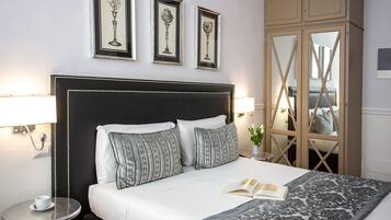 Un letto rifatto con precisione, con una testiera nera, due lampade ai lati e un quadro incorniciato sopra.