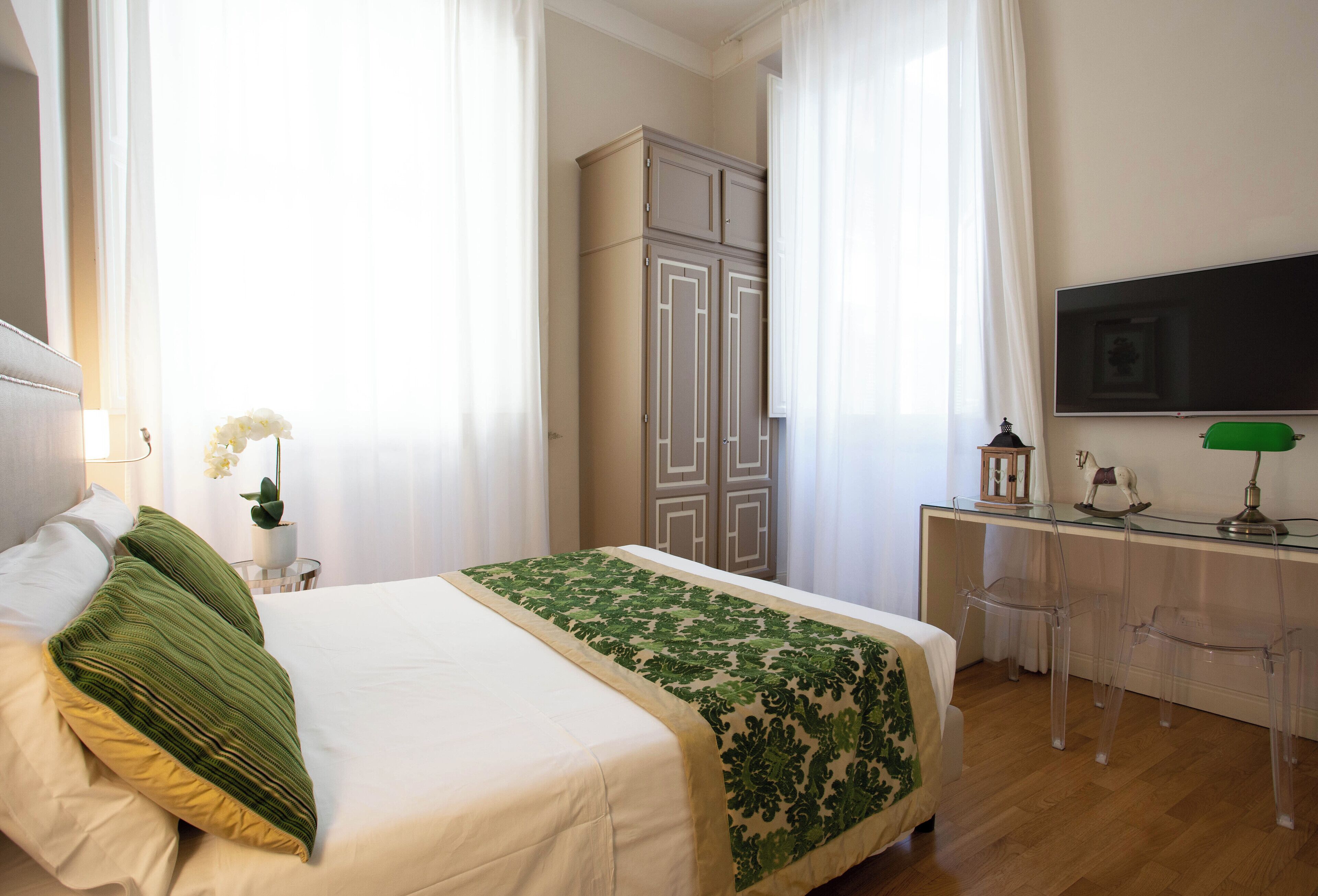 Une chambre à coucher comprenant un lit, un bureau, une télévision et une armoire.