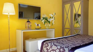 Un dormitorio con cama, mesita de noche, lámpara, espejo y un florero con flores.