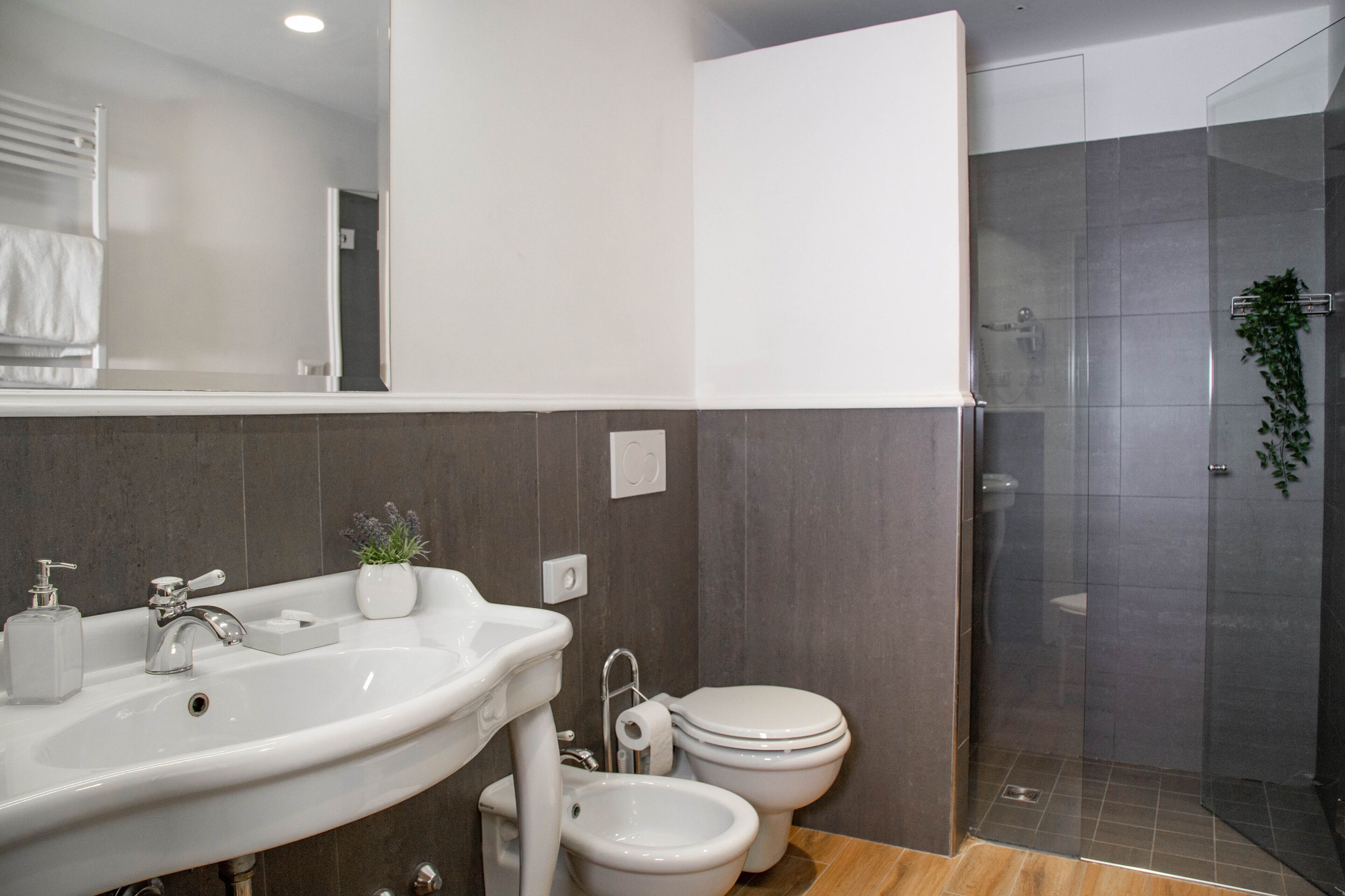 A modern bathroom with a sink, bidet, toilet, and a glass-enclosed shower.