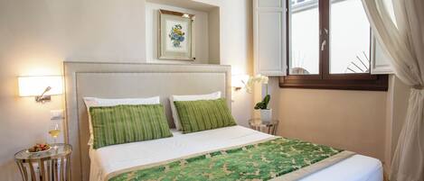 A neatly made bed with a green and white bedspread, a bedside table with a glass top, and a framed picture on the wall.