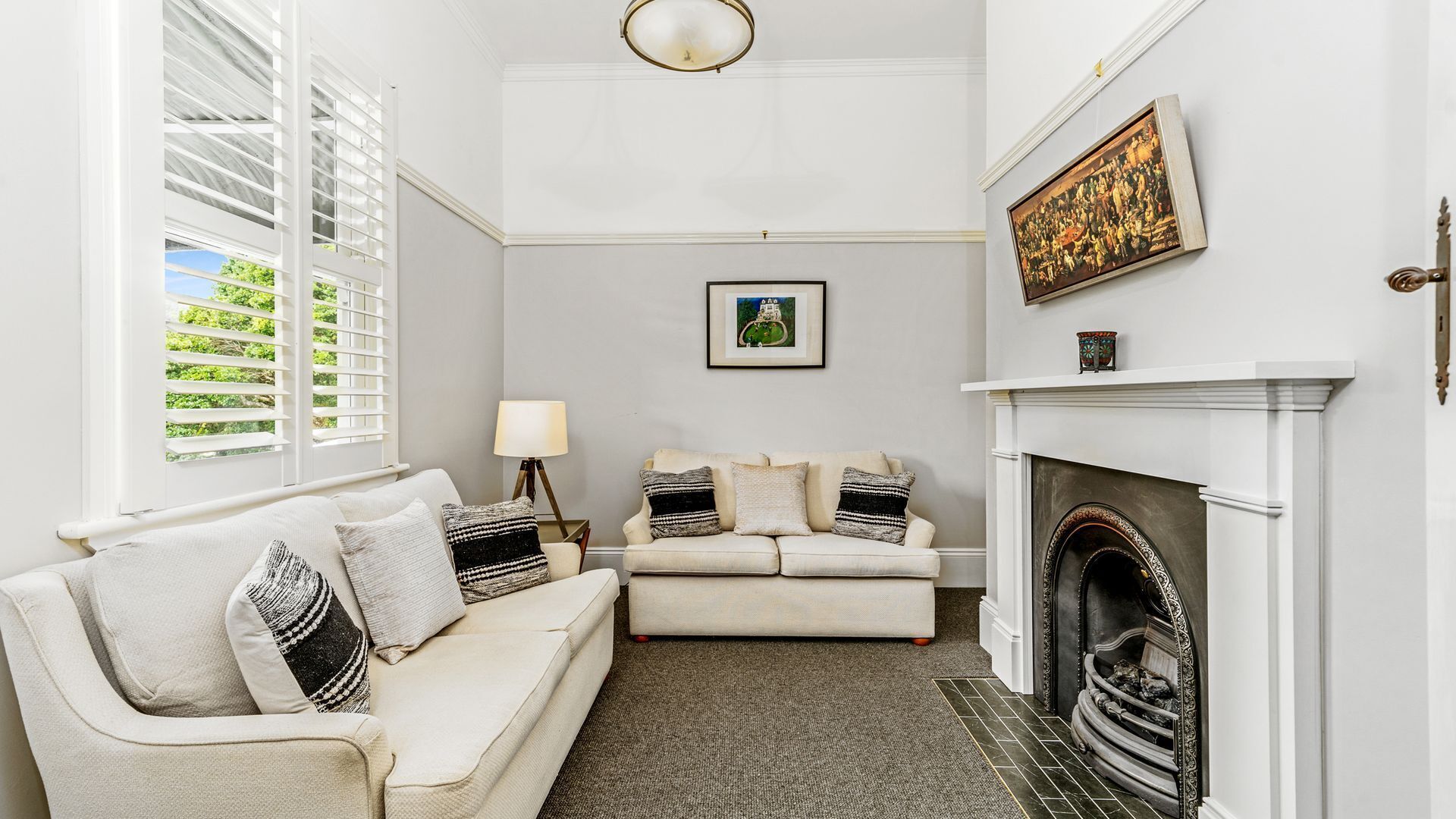 A living room with a fireplace, a sofa set, a lamp, and a framed picture on the wall.