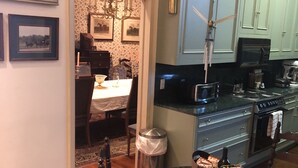 Een keuken met lichtblauwe kastjes, een eethoek met een tafel en stoelen, en een kroonluchter.