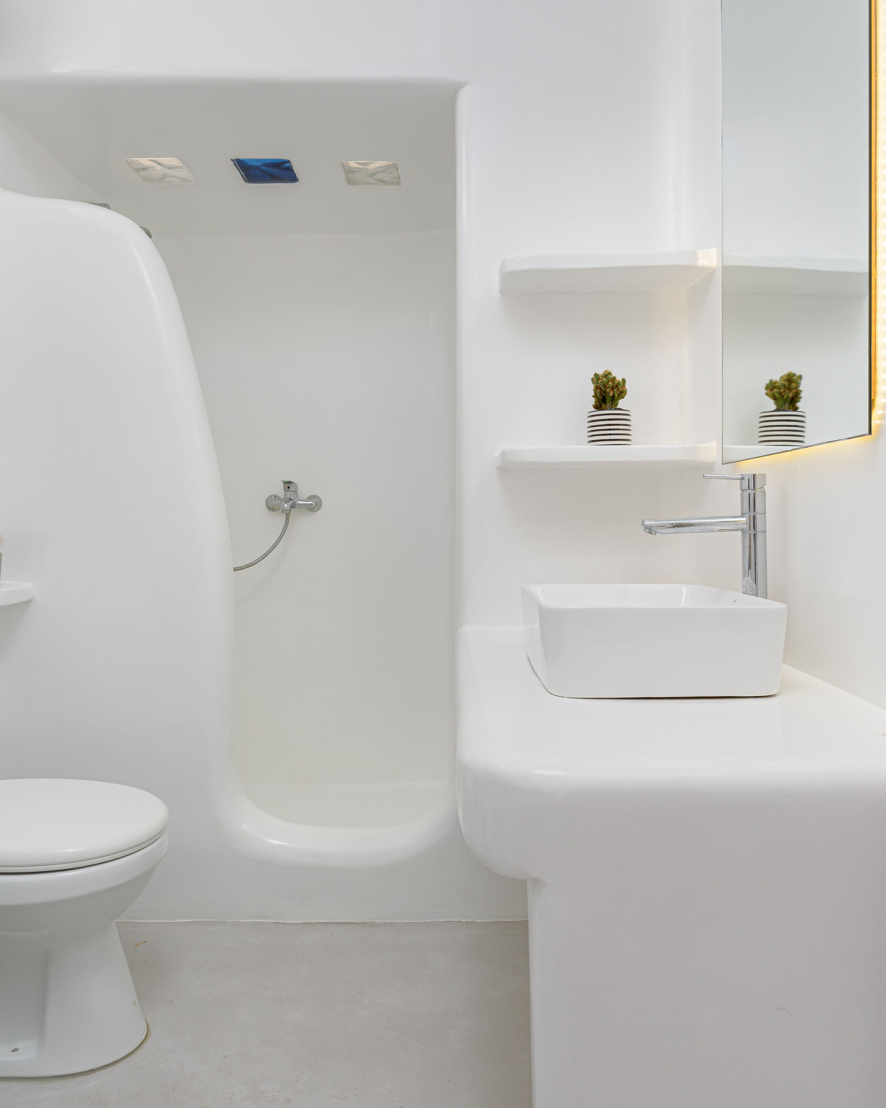 Un baño moderno con inodoro blanco, bañera y lavamanos con espejo.