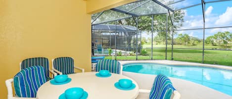 Enjoy al fresco dining with a view of the surrounding landscape from this outdoor dining area, featuring a round table and comfortable seating.
