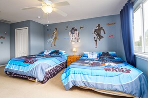 A bedroom with two beds, Star Wars-themed bedding, and wall decals.