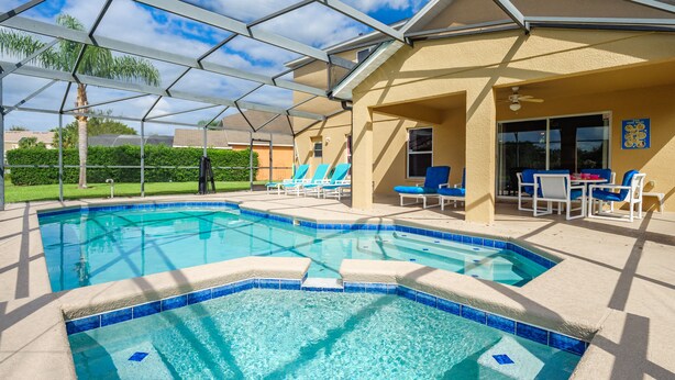 A swimming pool with a glass enclosure, lounge chairs, and a covered seating area. - Luxury 5 bed 4 bath SW facing pool with conservation and lake view (Clermont)