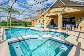A swimming pool with a glass enclosure, lounge chairs, and a covered seating area. - Luxury 5 bed 4 bath SW facing pool with conservation and lake view (Clermont)