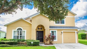 A two-story house with a beige exterior, a black front door, and a garage. - Luxury 5 bed 4 bath SW facing pool with conservation and lake view (Clermont)