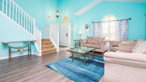 A living room with a staircase, a glass coffee table, and a beige sofa. - Luxury 5 bed 4 bath SW facing pool with conservation and lake view (Clermont)