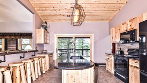 A kitchen with wooden cabinets, a central island, and a view to the outdoors.