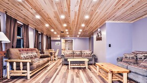 A cozy living room with a wooden ceiling, a sofa, a loveseat, and a coffee table.