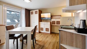Cocina compacta con comedor, armarios de madera, estufa integrada y ventana con vista a la ciudad.