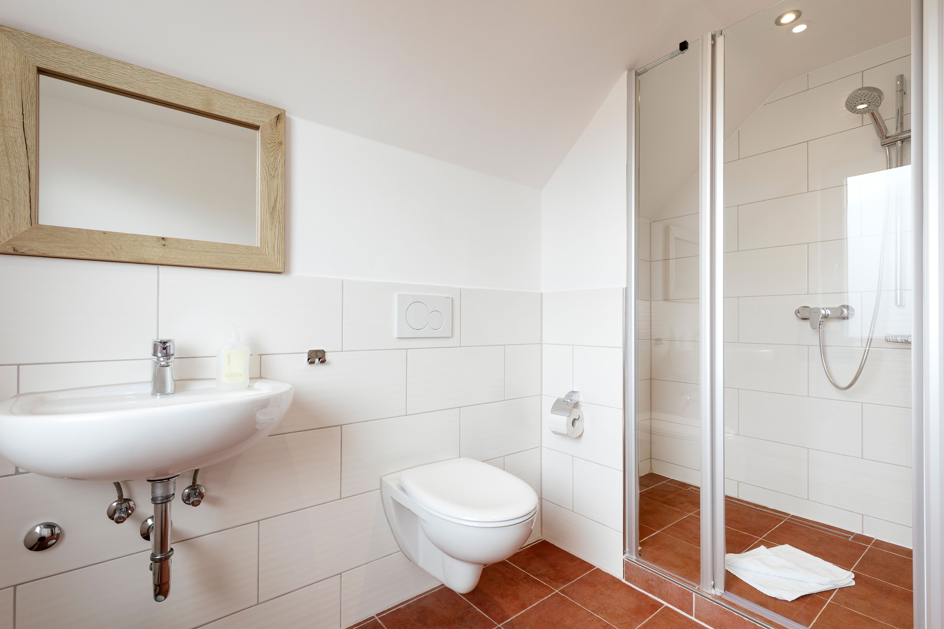 A bathroom with a sink, toilet, and glass shower enclosure.