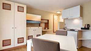 Una cocina moderna con armarios blancos, estufa integrada y un comedor con mesa y sillas blancas.