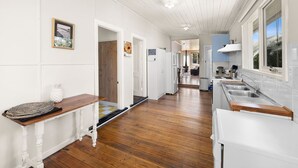 A kitchen with wooden flooring, white cabinetry, and a window with a view.
