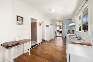 A kitchen with wooden flooring, white cabinetry, and a window with a view.