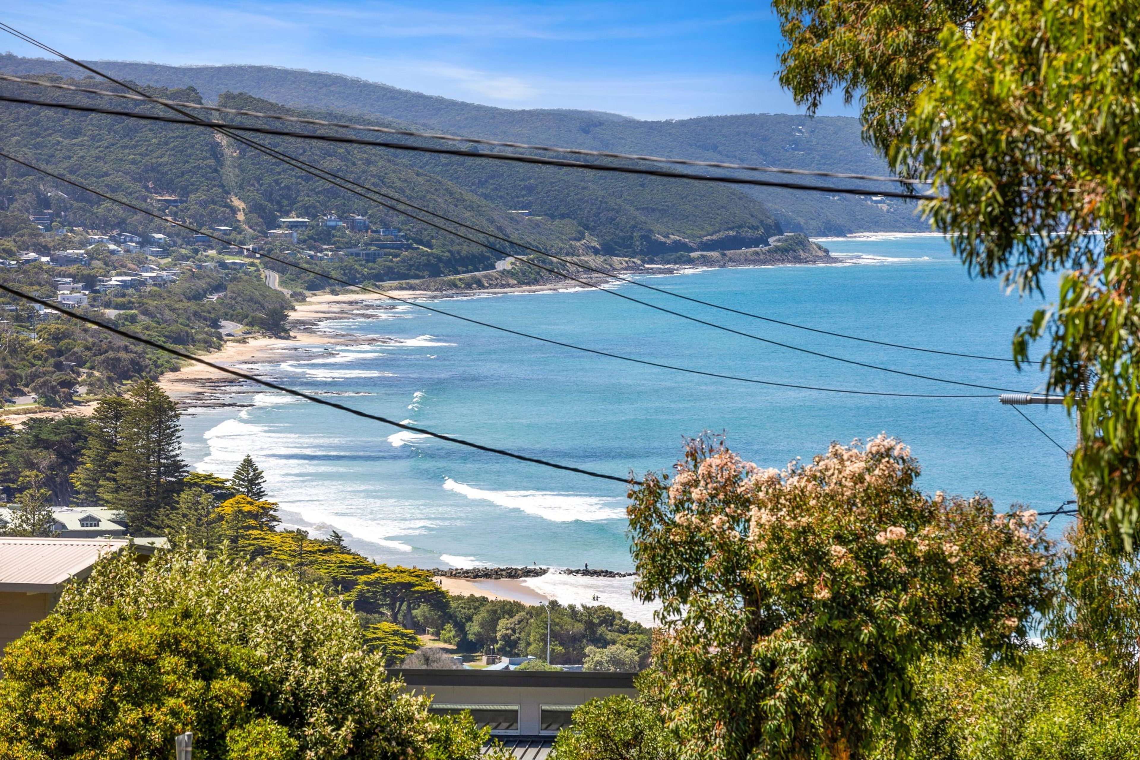 A coastal landscape with a view of the ocean, hills, and a bridge.