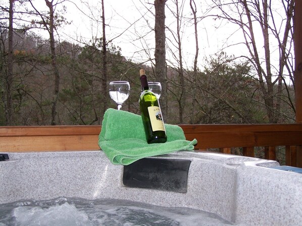 Ein Whirlpool mit einer Weinflasche und einem Glas auf einem grünen Handtuch.