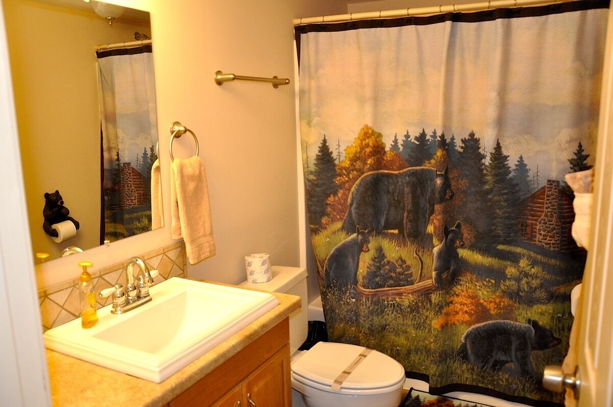 Bagno con lavandino, wc e tenda della doccia raffigurante orsi nella foresta.