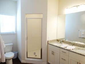A bathroom with a toilet, a shower enclosure, a sink with a mirror, and a towel hanging on the wall. - Nov Special at Lucaya - 4 bed 3bath Id:57055 (Kissimmee)