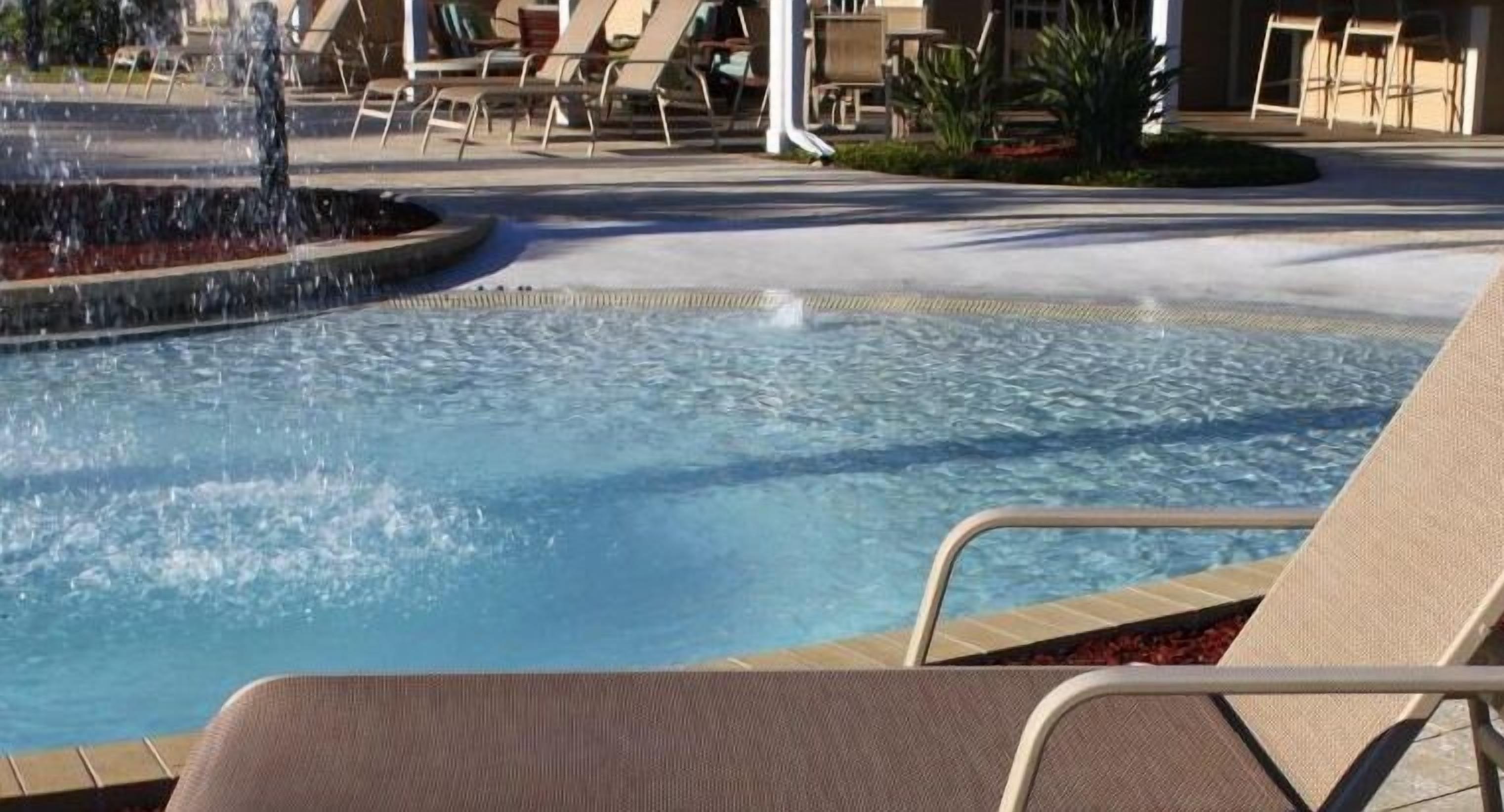 A pool area with lounge chairs and a water feature.