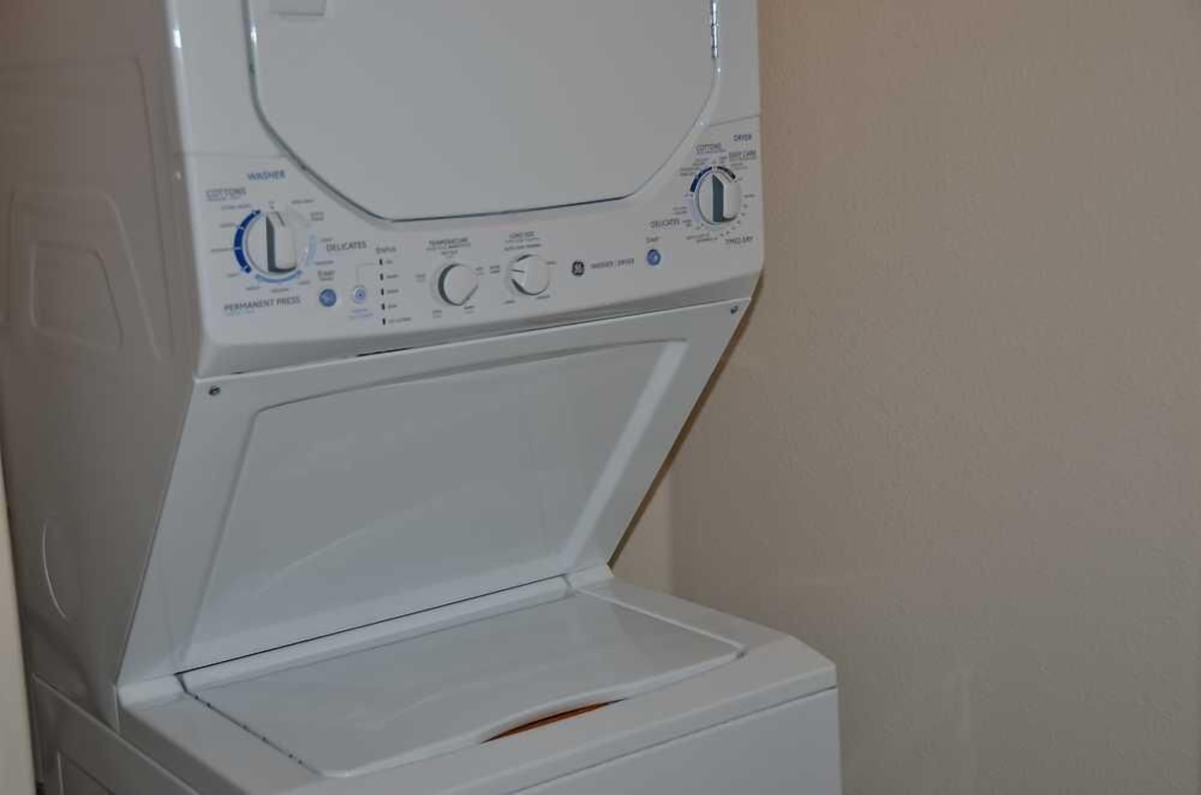 A white washing machine with control panel, open door, and no visible interior.