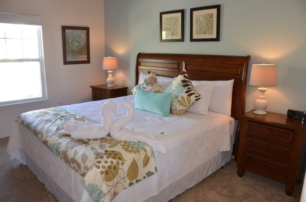 A neatly made bed with a floral bedspread, two bedside lamps, and a nightstand with a lamp.