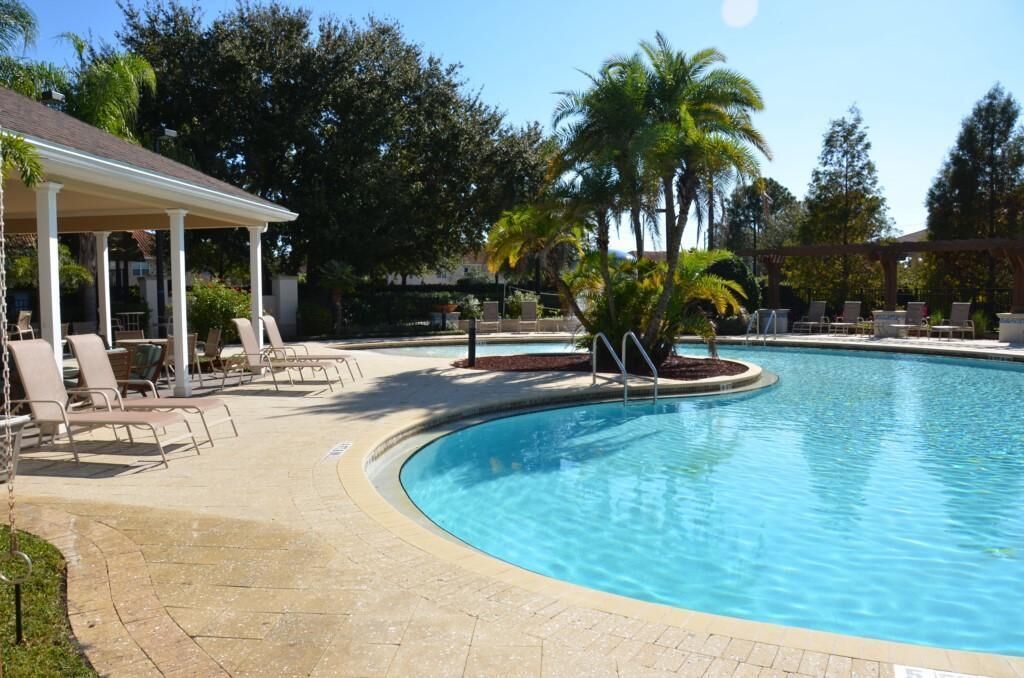 A swimming pool with lounge chairs and a covered seating area.